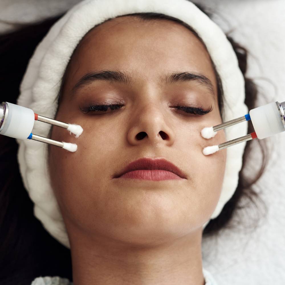 doctor doing face toning of beautiful female